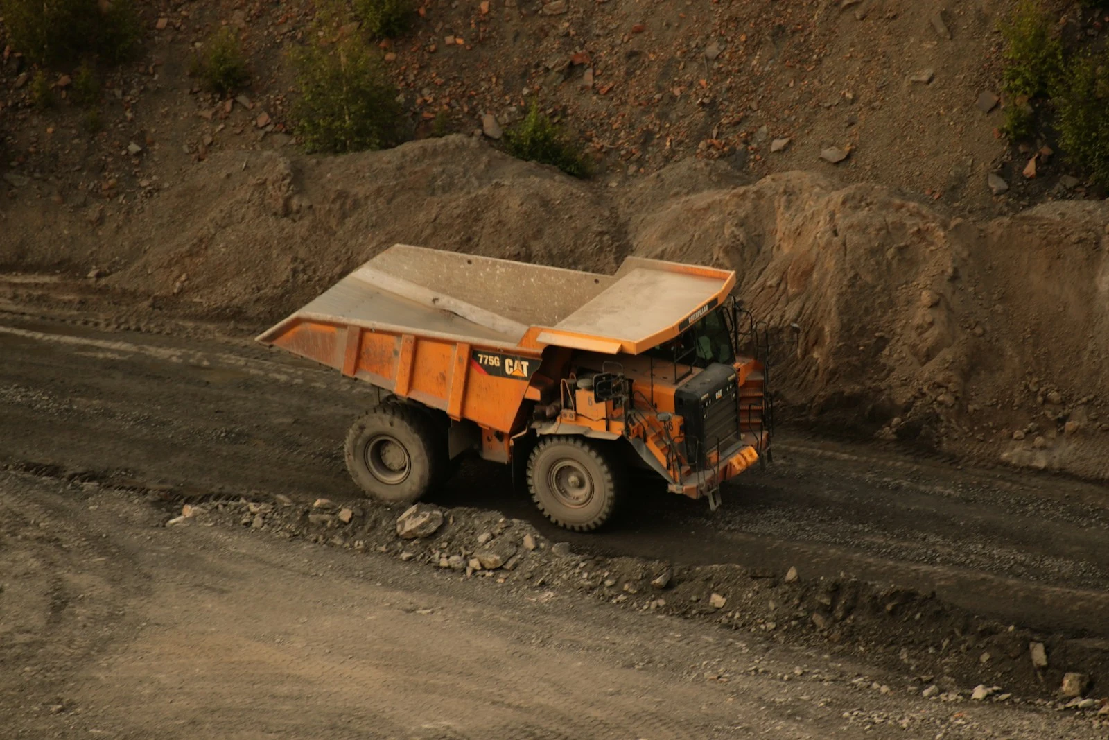Orange dump truck on dirt road for site debris removal