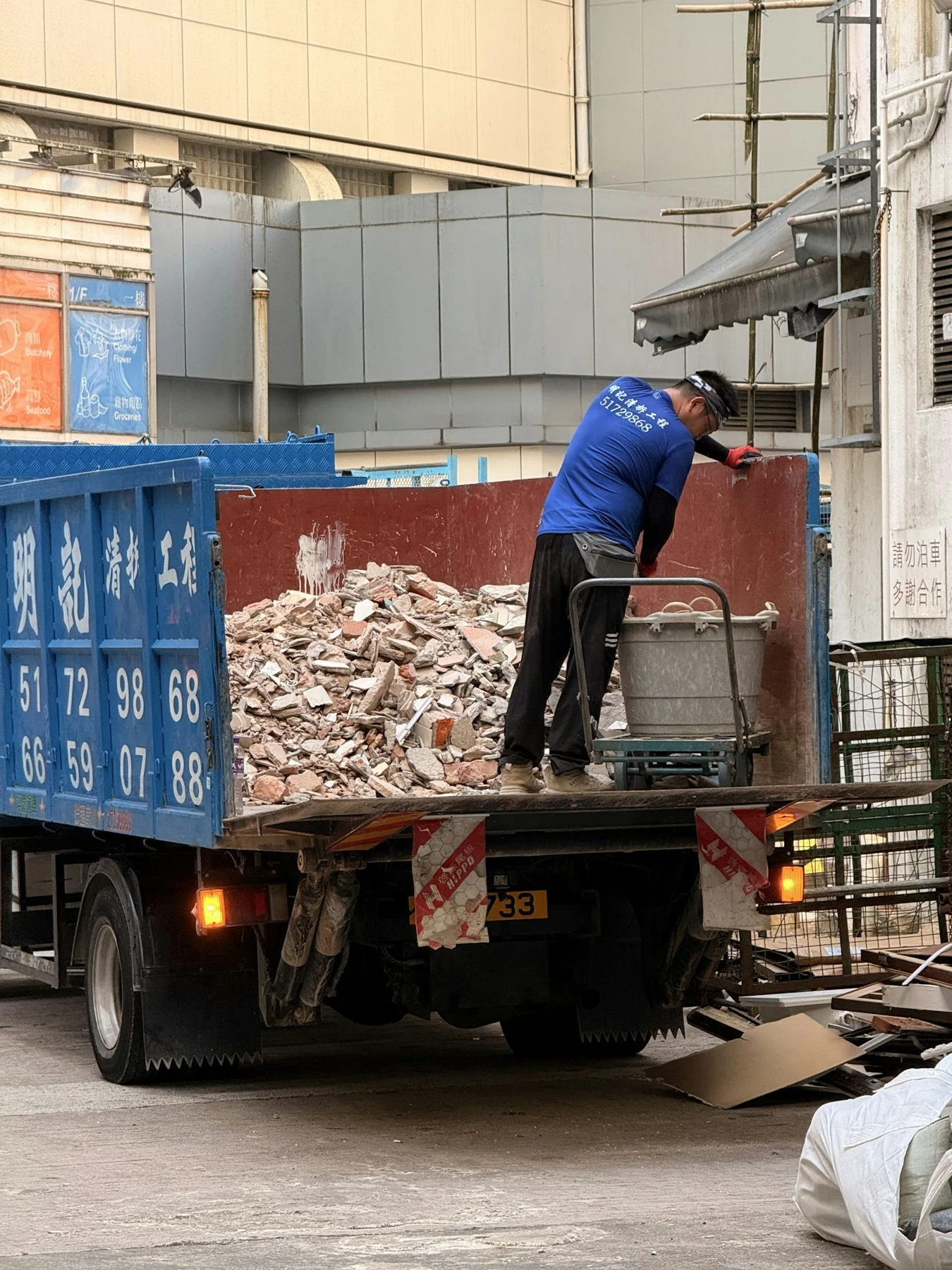 Worker loading debris into a grapple truck for hauling